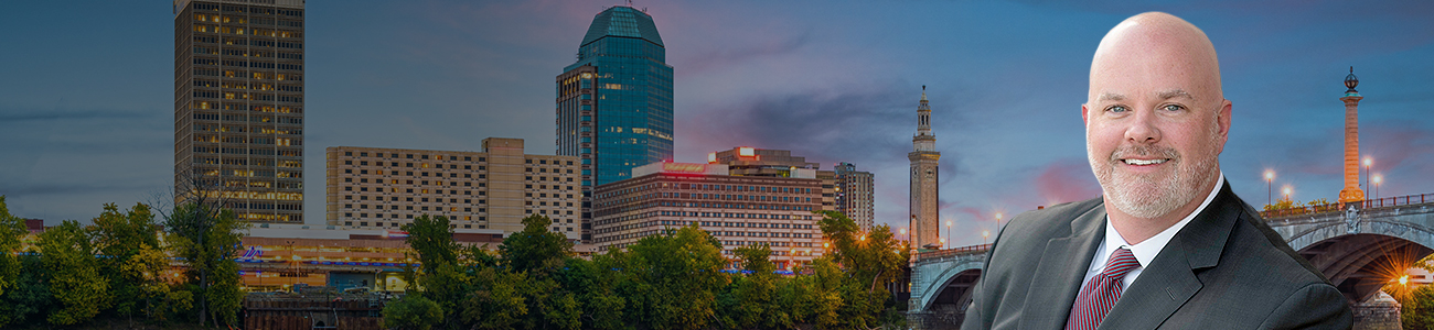 Foto of Dan Daly in front of Springfield, Massachussetts, USA downtown skyline on the river