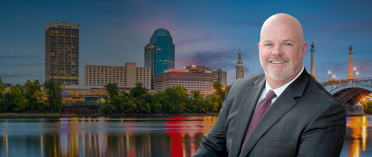 Foto of Dan Daly in front of Springfield, Massachussetts, USA downtown skyline on the river